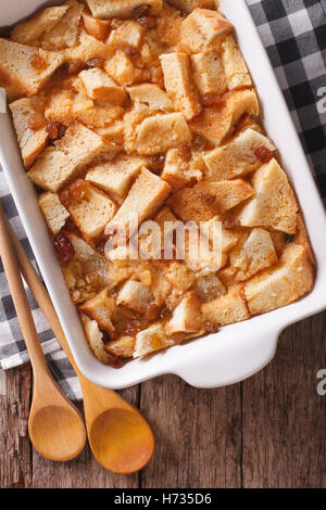 Delicious English bread pudding with raisins close up in baking dish on the table. Vertical view from above Stock Photo