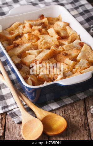 Freshly baked bread pudding with raisins close up in baking dish on the table. Vertical Stock Photo