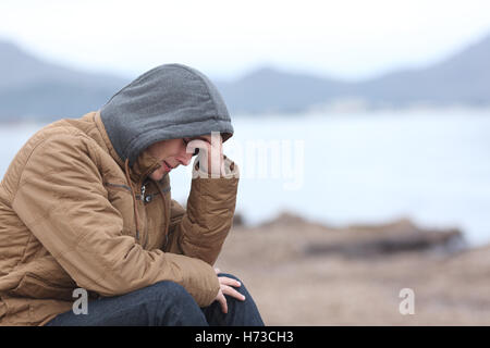 Worried teenager guy on the beach in winter Stock Photo