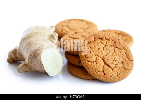 Fresh cut root ginger next to a pile of ginger biscuits isolated on white. Stock Photo