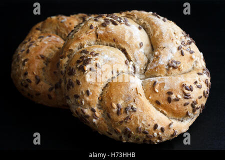 Whole wheat kaiser rolls with sesame seeds on black surface. Stock Photo