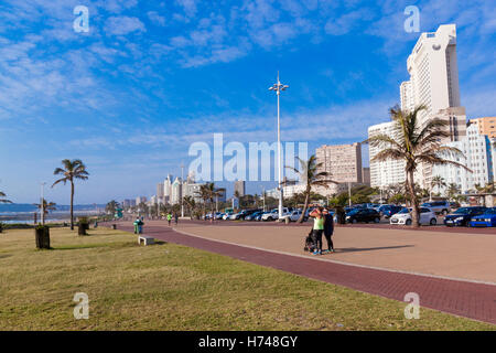 people enjoy  early morning stroll on quiet promenade on Golden Mile beach front against city skyline Stock Photo