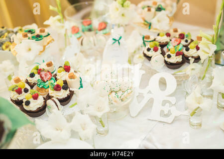 Delicious and tasty dessert table with cupcakes shots at reception closeup Stock Photo