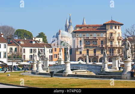 The beautiful statues of Prato della Valle, surrounded by the street market with the towers and domes of Basilica Stock Photo