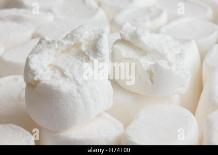 Single white marshmallow torn in two sitting on other marshmallows. Stock Photo