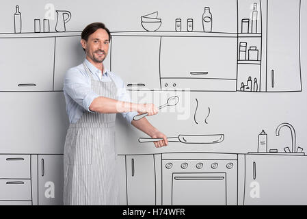 Pleasant good looking man holding a frying pan Stock Photo
