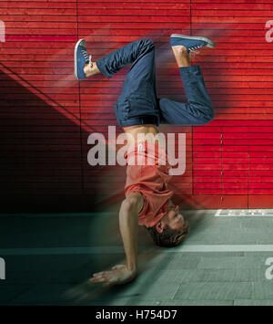 Break dancer doing handstand against colorful wall background Stock Photo
