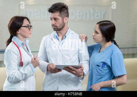 Three doctors using a tablet in bright office Stock Photo