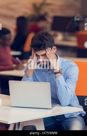 Software Developer sitting with laptop computer in startup office Stock Photo