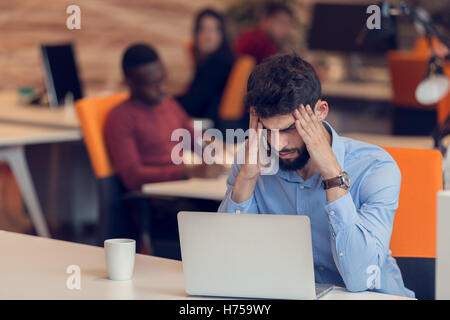 Software Developer sitting with laptop computer in startup office Stock Photo