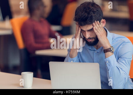 Software Developer sitting with laptop computer in startup office Stock Photo