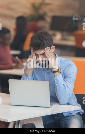 Software Developer sitting with laptop computer in startup office Stock Photo