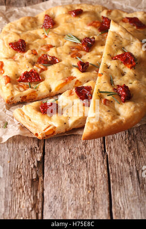 Sliced bread Italian focaccia with sun-dried tomatoes and rosemary close up on the table. vertical Stock Photo