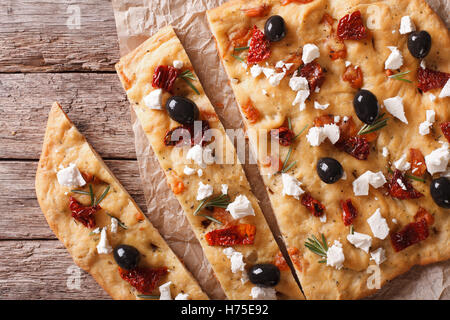 Focaccia with dried tomatoes, feta and olives on the table closeup. horizontal view from above Stock Photo