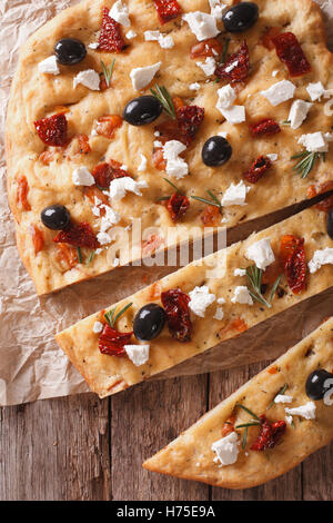 Focaccia with dried tomatoes, feta and olives on the table closeup. vertical view from above Stock Photo