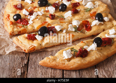 Sliced Italian focaccia with dried tomatoes, feta and olives on the table. closeup horizontal Stock Photo