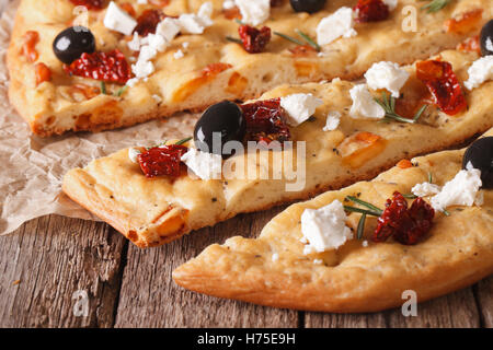 Sliced focaccia with dried tomatoes, feta and olives on the table. macro horizontal Stock Photo
