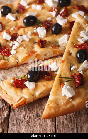 Focaccia with dried tomatoes, feta and olives on the table. macro vertical Stock Photo