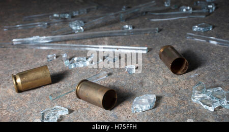 Empty shells from a handgun with glass on dark concrete Stock Photo