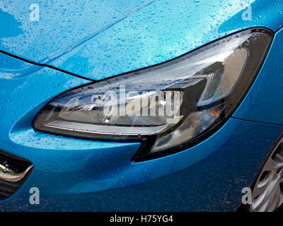 Close up view of metallic blue 2016 model Vauxhall Corsa car with water drops on body and headlights Stock Photo