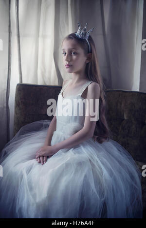 Portrait of a girl sitting on a chair dressed in a princess outfit Stock Photo
