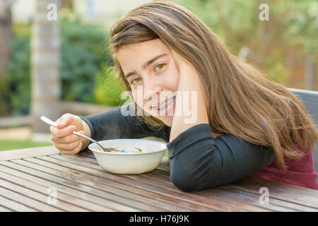 A teenage girl with braces on her teeth enjoying hot chicken soup (a.k.a. the Jewish Penicillin) in a cold autumn day Stock Photo