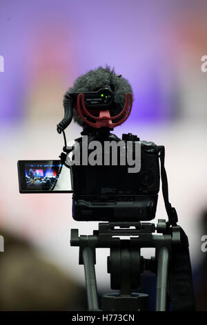A digital slr video camera on a tripod with microphone recording video at an event Stock Photo