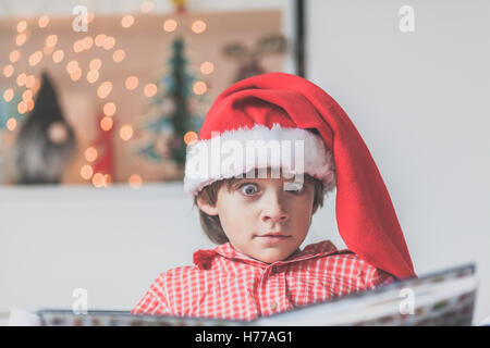 Portrait of a boy  reading in a christmas santa hat Stock Photo