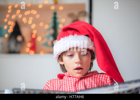 Portrait of a boy  reading in a christmas santa hat Stock Photo