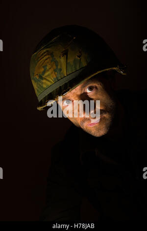 Portrait of a battle stressed American soldier from the Vietnam War, against a dark background. Stock Photo
