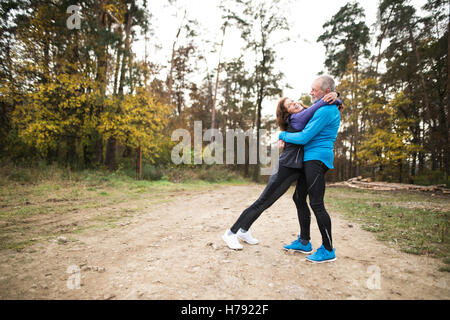 Beautiful senior couple running outside in sunny autumn forest Stock Photo