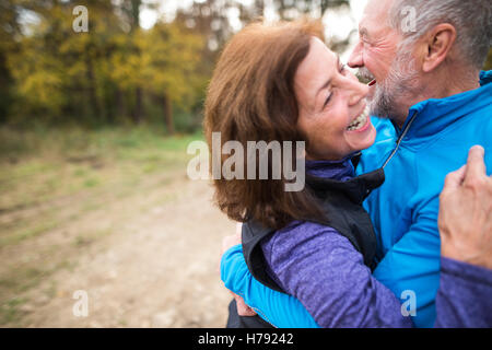 Beautiful senior couple running outside in sunny autumn forest Stock Photo