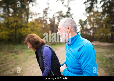 Beautiful senior couple running outside in sunny autumn forest Stock Photo