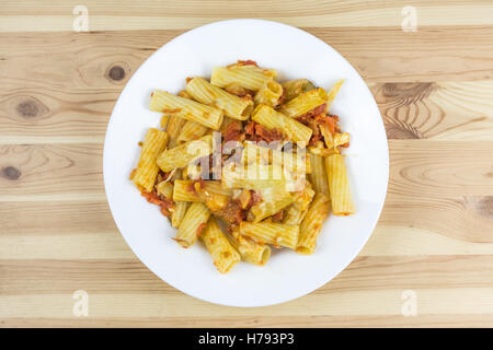 Top view of baked tortiglioni pasta with tomato sauce, mozzarella and parmesan cheese in the plate on the wood table Stock Photo
