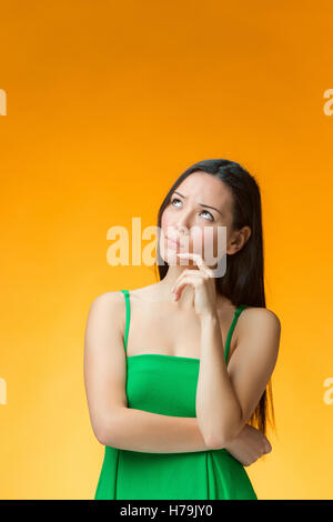 The thinking Chinese girl on yellow background Stock Photo