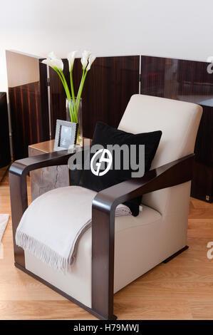 Black cushion with symbol on dark wood polished armchair with half-folding-screen Stock Photo
