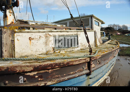 an old boat stuck in the mud abandoned with a ghostly reflection in the window of another boat Stock Photo