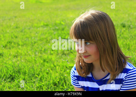 little fashionable girl smirks on the green grass background Stock Photo