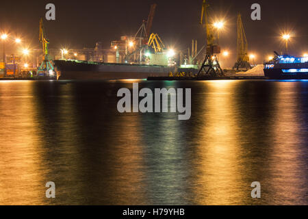 Cargo vessel is moored  at container terminal of port  Odessa, Ukraine. Crane lights are on background. Night view picture Stock Photo