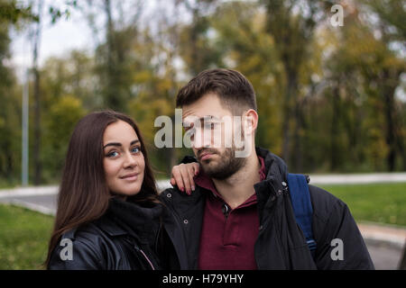 Closeup shot of young beautiful stylish couple in autumn park. man is looking at her petulantly Stock Photo