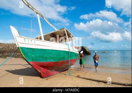 SALVADOR, BRAZIL - FEBRUARY 23, 2016: Brazilian fishermen perform maintainance of a traditional brightly painted boat. Stock Photo