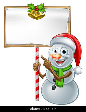 Christmas snowman cartoon character in Santa hat holding a wooden scroll sign and pointing Stock Photo