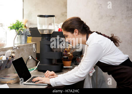 Cute Caucasian busy working with laptop on coffee shop counter Stock Photo