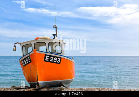 Orange Fishing Boat on Branscombe beach, Devon UK on a bright and sunny summer's day. Stock Photo