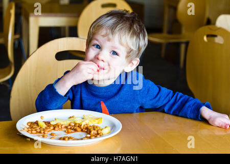 Young boy eating chips and baked beans in a restaurant Stock Photo