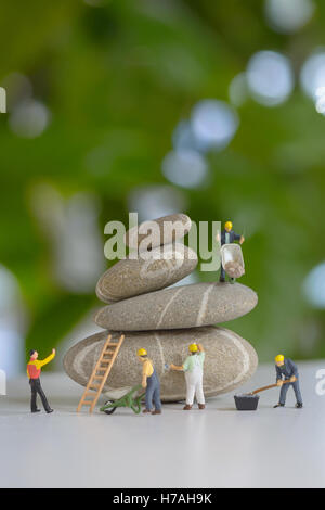 Pebbles stack and figurines of construction workers Stock Photo