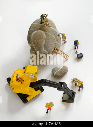 Pebbles stack and figurines of construction workers Stock Photo