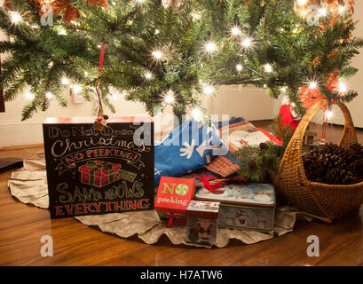 Presents underneath a lit Christmas tree on a hardwood floor Stock Photo