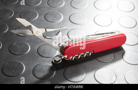 Scissors out on a red pocket knife with a lot of tools Stock Photo