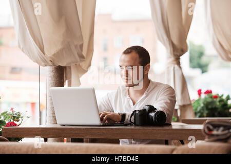 Man is looking at laptop with excitement. Photographer is choosing photos from a shoot Stock Photo